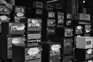 Monochrome photo of stacked safes with price tags in a store setting.